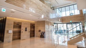 A modern hotel lobby with a glass staircase, elevators, and a reception desk. - IBC Hotel (Seoul)