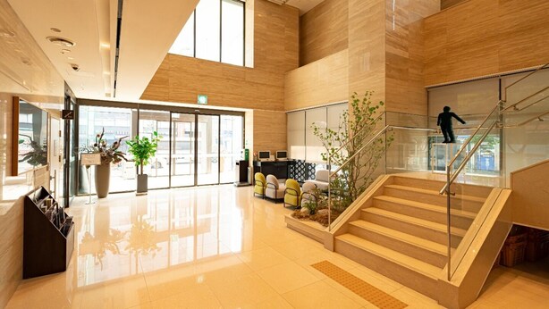 A modern hotel lobby with a glass staircase, seating area, reception desk, and large windows. - IBC Hotel (Seoul)