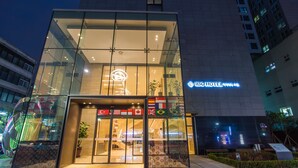 A modern hotel entrance with glass doors, a sign indicating it is the IBC Hotel, and multiple flags displayed outside. - IBC Hotel (Seoul)