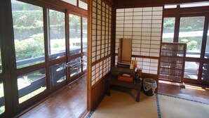 A traditional Japanese room with tatami flooring, sliding doors, and a view of a garden. - Takaosou (Yufu)