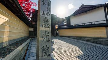 A stone monument with Japanese characters, a traditional building with a tiled roof, and a pathway with a stone border.