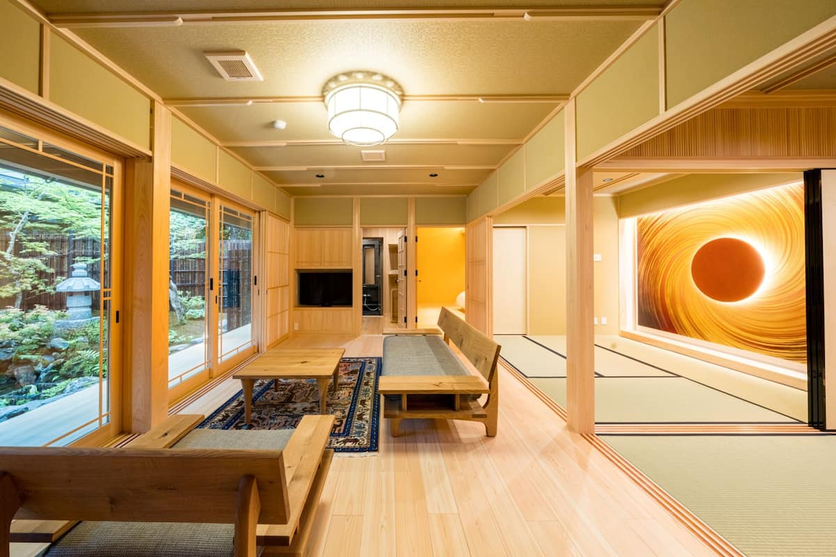 A traditional Japanese room with tatami flooring, a low table, benches, and sliding doors.