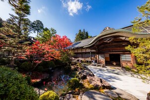 Un edificio japonés tradicional con estructura de madera y un sendero de piedra que lleva a un estanque.