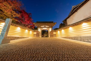 Un torii japonés tradicional al anochecer, con un camino pavimentado que conduce hacia él.