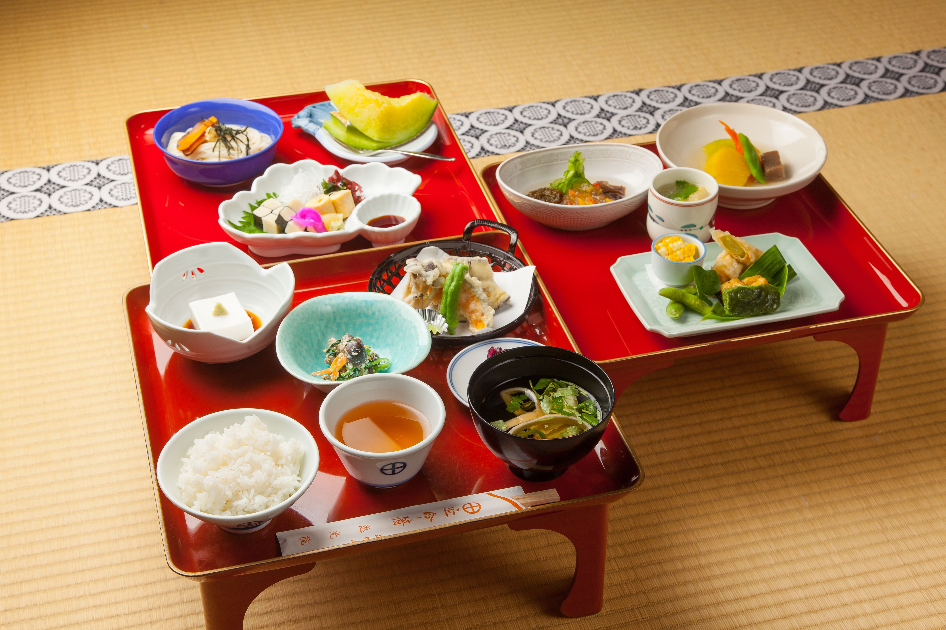 Una comida tradicional japonesa sobre una bandeja roja, con diversos platos que incluyen arroz, sopa y sashimi.