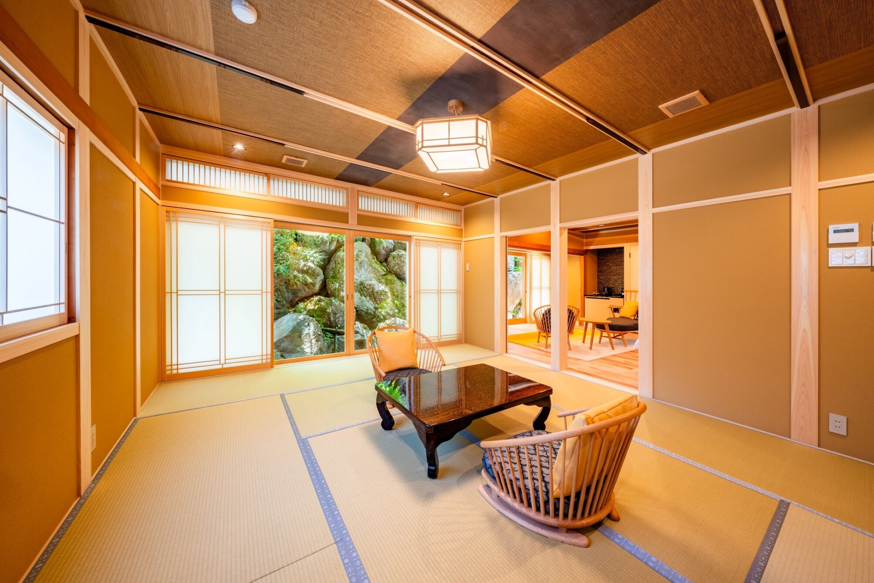 A traditional Japanese room with tatami flooring, a low table, and a rocking chair.