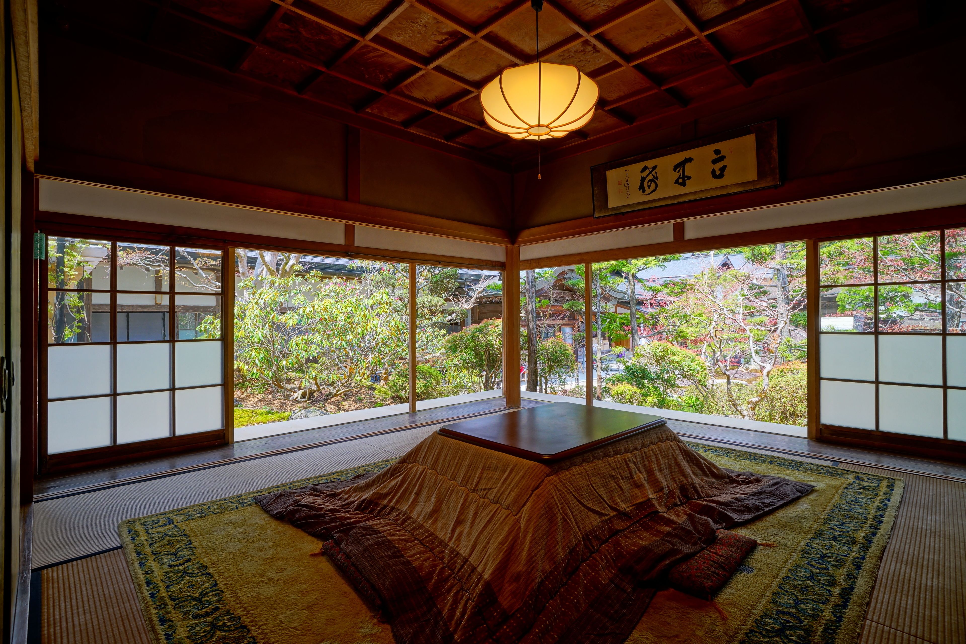 A traditional Japanese room with tatami flooring, sliding doors, and a view of a garden.