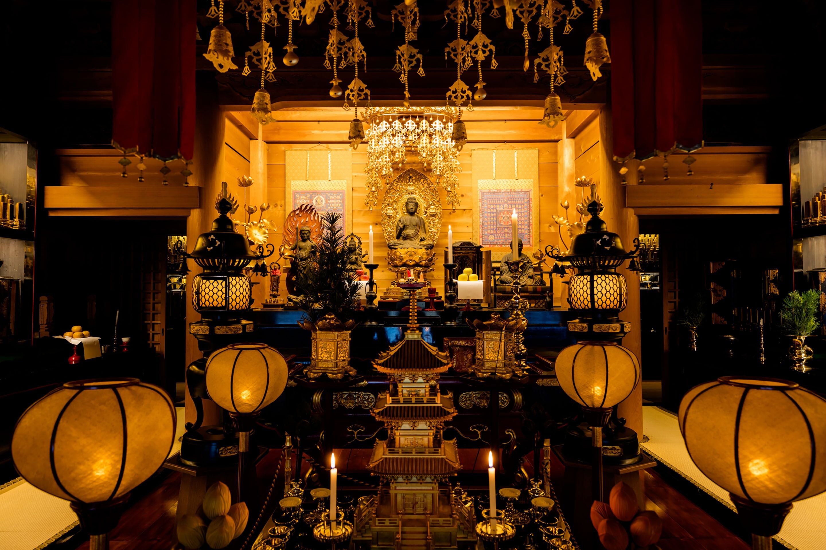 An ornate shrine with a central Buddha statue, surrounded by candles and traditional decorations.