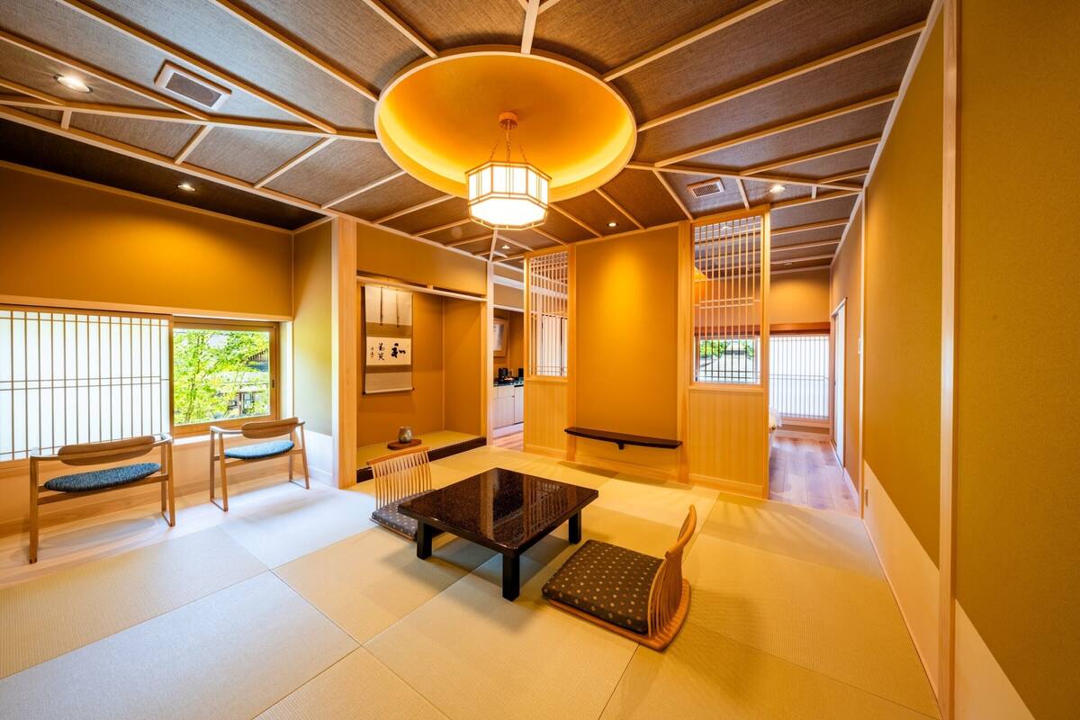 A traditional Japanese room with tatami flooring, a low table, and a wooden chair.