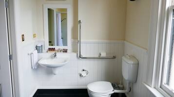 A bathroom with a white sink, toilet, and a mirror above the sink.