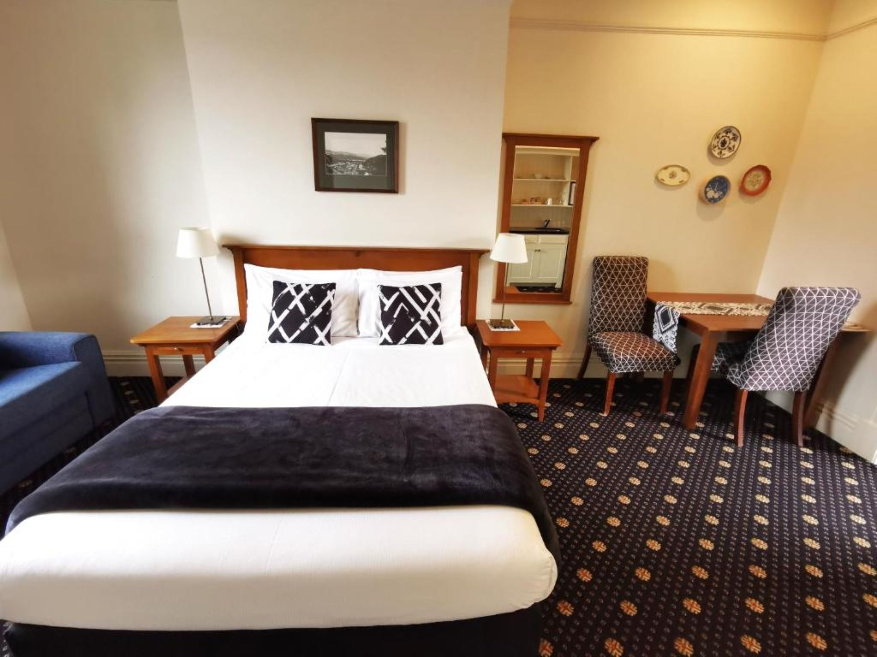 Une chambre d’hôtel avec un lit, un bureau, une chaise et une petite table.