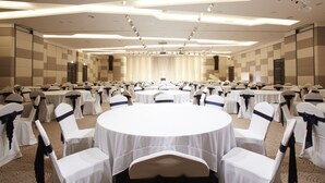 A conference room with round tables and white chairs, equipped with ceiling lights and a stage. - Hotel Prumir (Hwaseong)