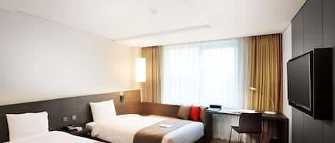 Habitación de hotel con dos camas, un escritorio, una silla, un televisor y una ventana con cortinas.