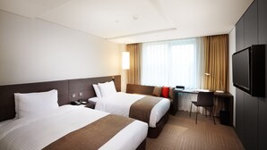 A hotel room with two beds, a desk, a chair, a TV, and a window with curtains. - Hotel Prumir (Hwaseong)