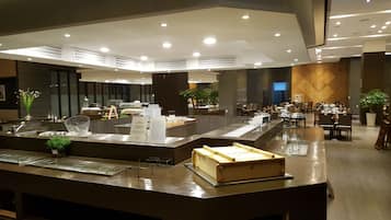 A modern hotel lobby with a reception desk, seating area, and a large plant.