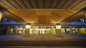 A modern building entrance with a wooden canopy and glass doors. - Hotel Prumir (Hwaseong)