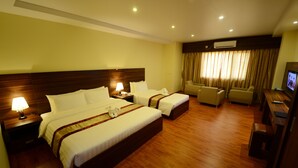 Habitación de hotel con dos camas, un escritorio, una silla y un televisor.