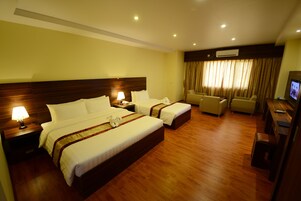 Habitación de hotel con dos camas, un escritorio, una silla y un televisor.