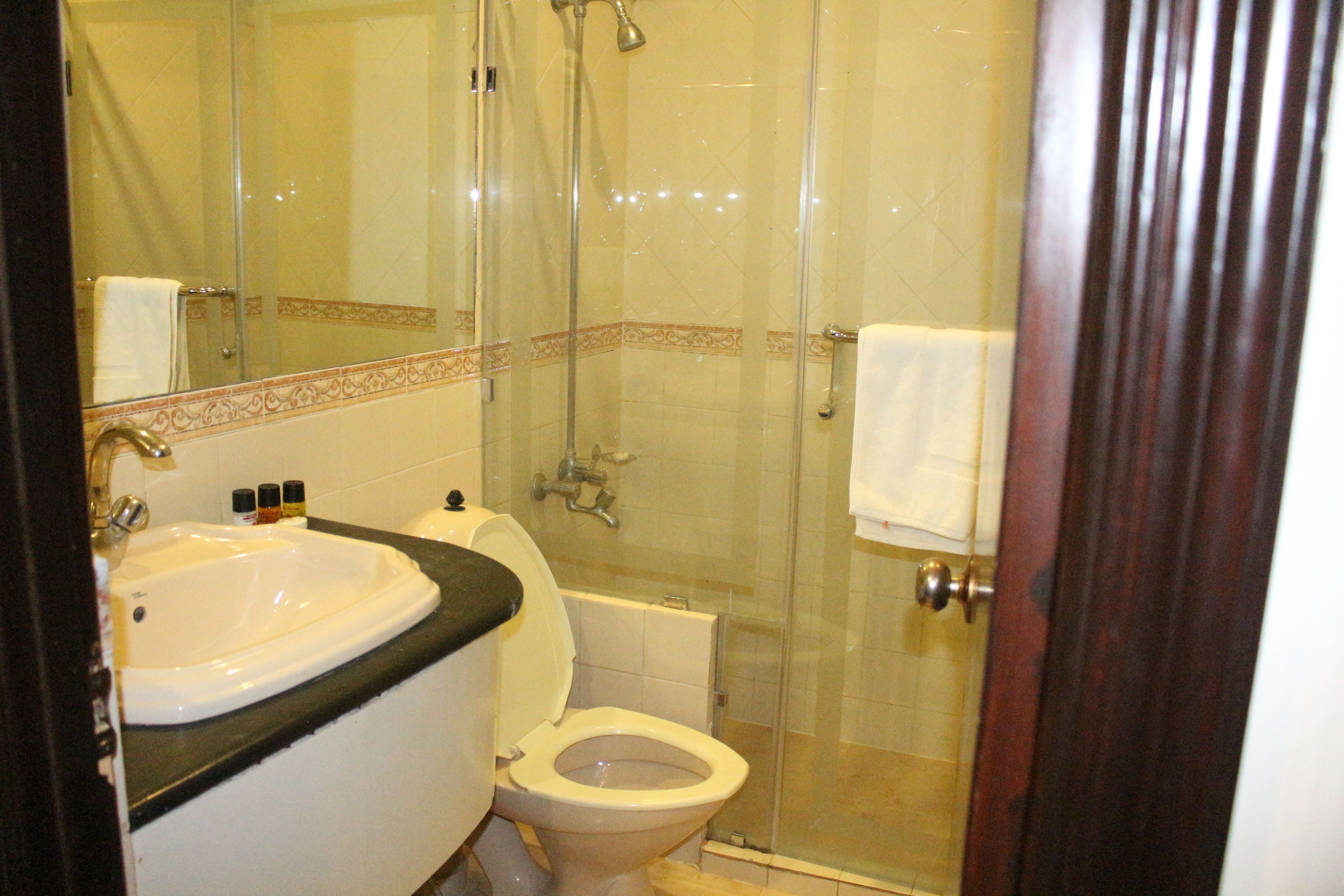 A bathroom with a glass-enclosed shower, a white sink, and a toilet.