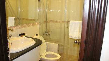 A bathroom with a glass-enclosed shower, a white sink, and a toilet.