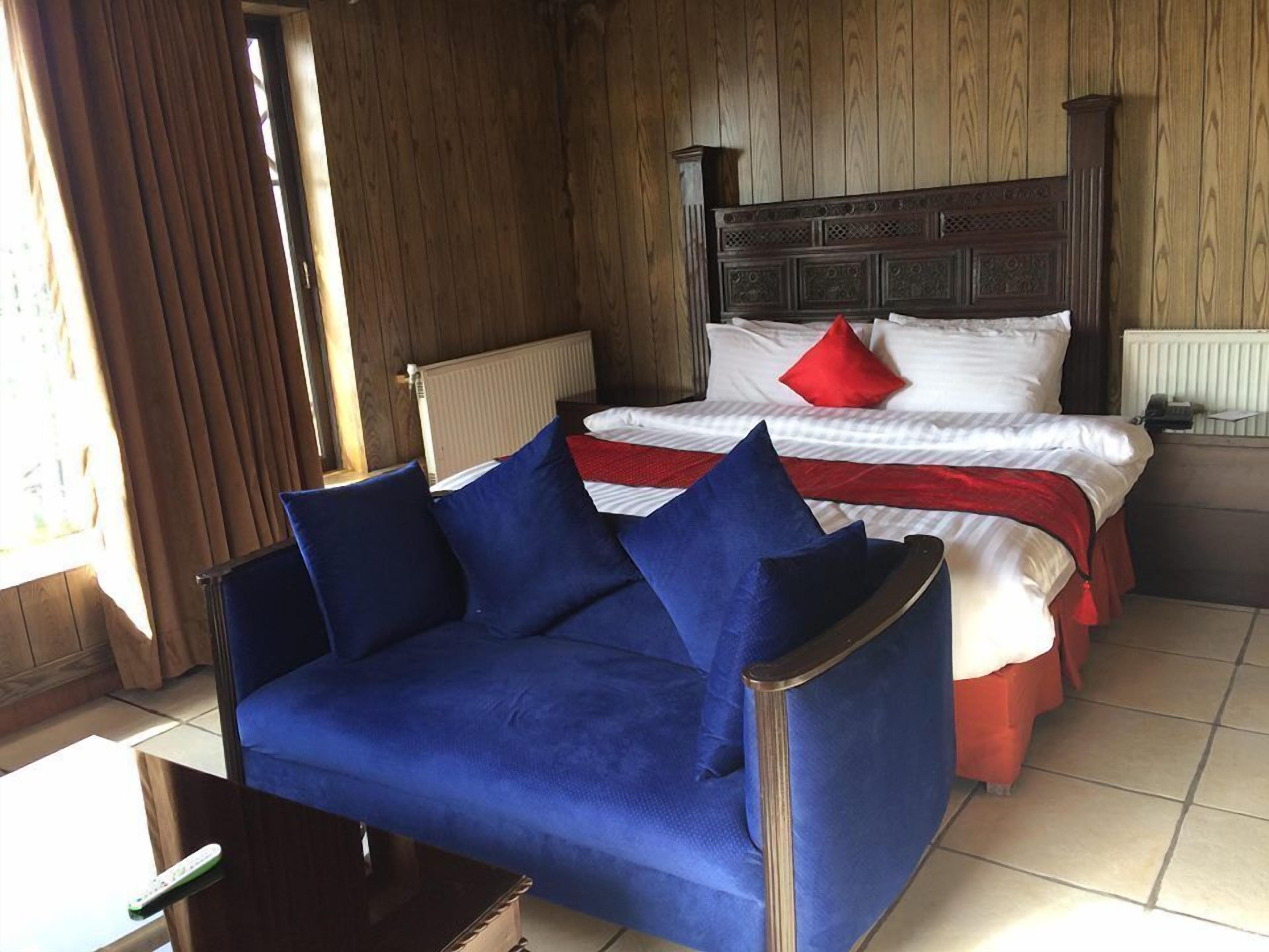 Una habitación con una cama, un sofá azul y un cabecero de madera.