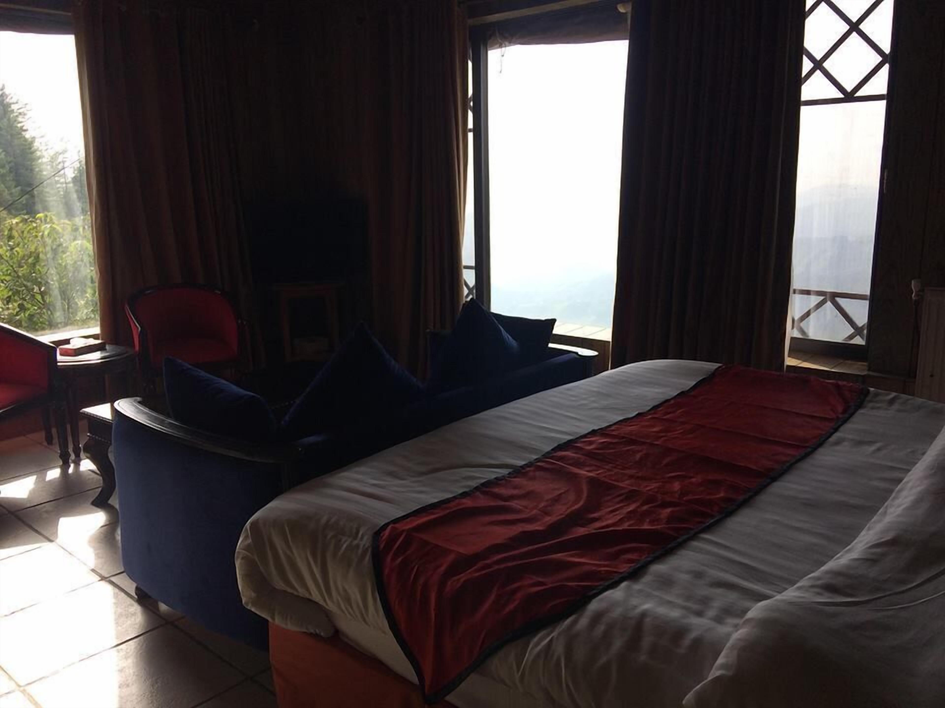 A bedroom with a large bed, a seating area with a chair and a table, and a view of the outdoors through a window.