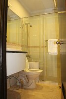 Un baño con inodoro, cabina de ducha de vidrio y un perchero para toallas.