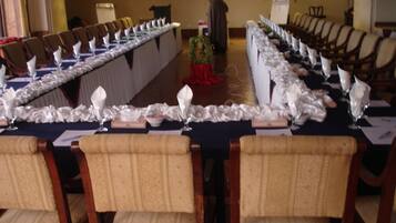 A long banquet table set for a formal event with rows of chairs and white tablecloths.