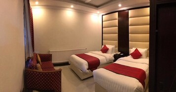 Habitación de hotel con dos camas, una silla y un radiador.