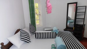 Una cama bien tendida con ropa de cama a rayas, un cabecero de madera y un espejo en la pared.
