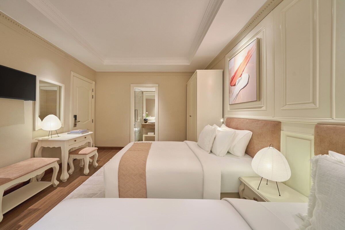 Une chambre d’hôtel avec un lit, une table de chevet, une lampe et un téléviseur fixé au mur.