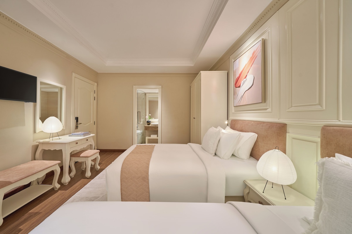 A hotel room with a bed, bedside table, lamp, and a television on the wall.