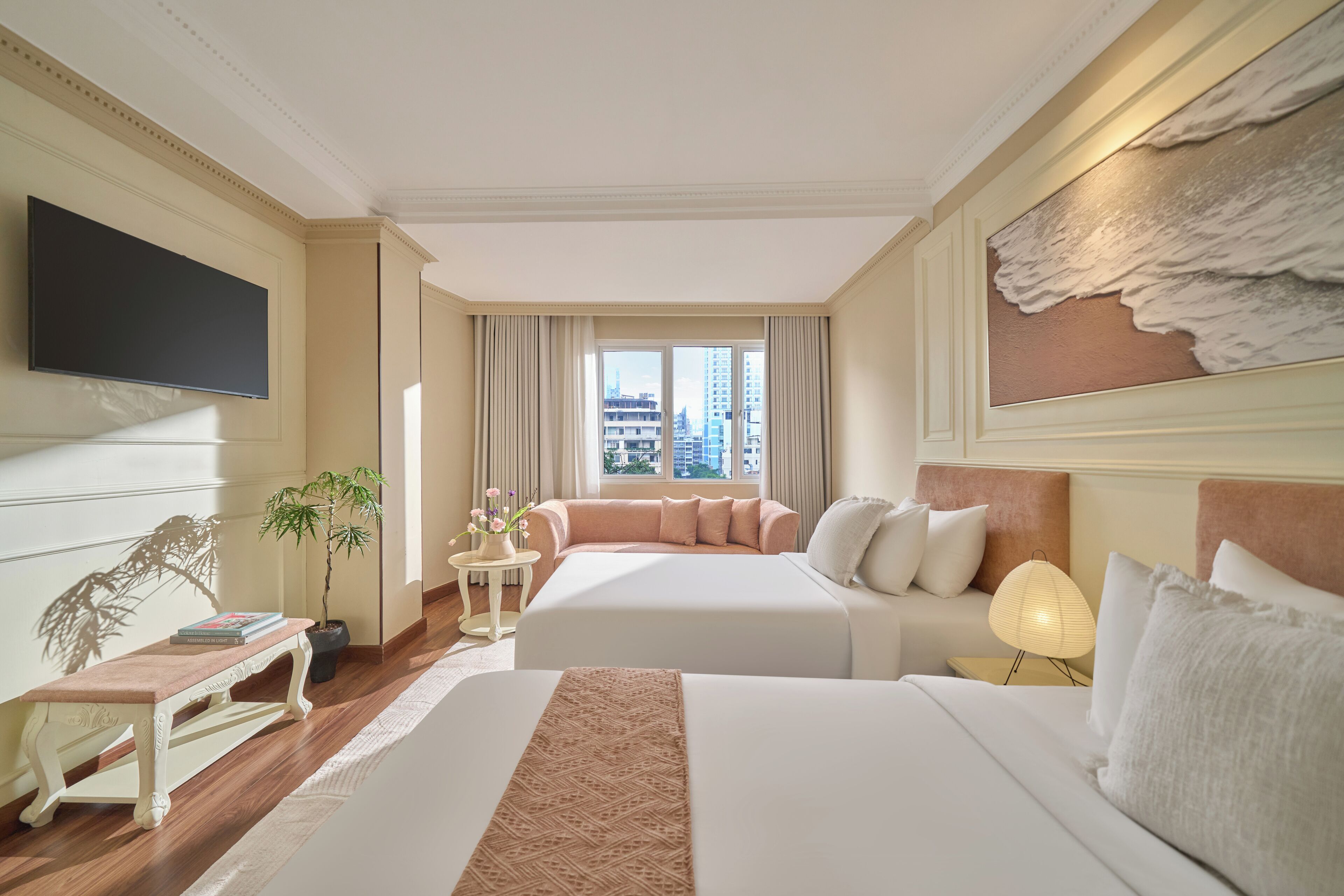 A hotel room with two beds, a flat-screen TV, a potted plant, and a view of the cityscape.