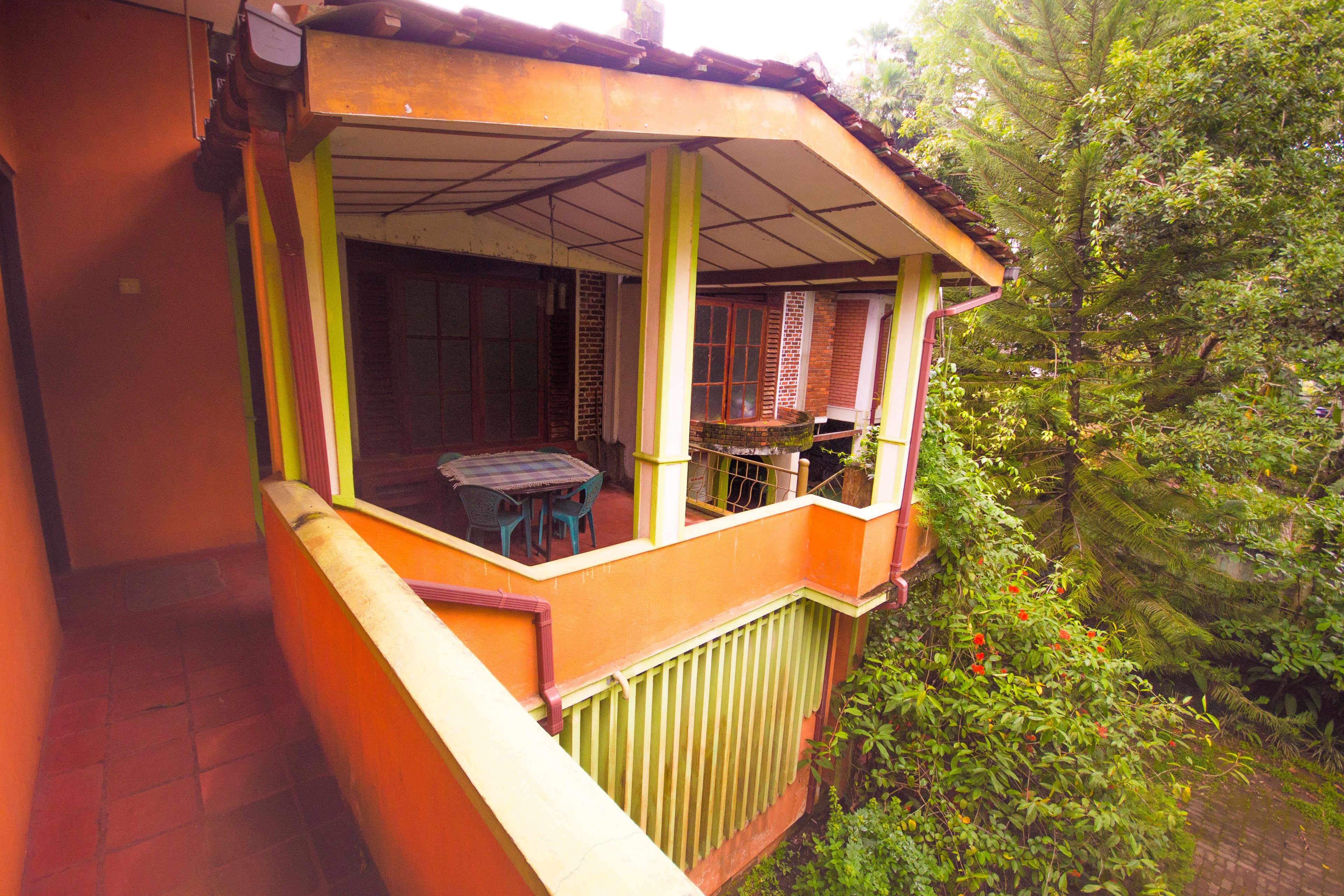 A balcony with a table and chairs, surrounded by greenery.