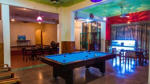 A pool table in a room with a green ceiling, wooden furniture, and a view through a glass door. - Hotel Gem Land (Ratnapura)