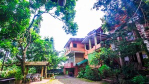 A courtyard with a gazebo, a brick pathway, and a building with a balcony. - Hotel Gem Land (Ratnapura)