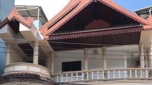 Un immeuble à plusieurs étages, de style architectural traditionnel, doté d’un balcon et d’une enseigne indiquant « MAISON D’HÔTES ».