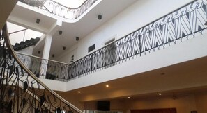 A multi-level interior with a staircase, geometric railing, and a high ceiling. - Cosy Hotel & Restaurant (Jaffna)