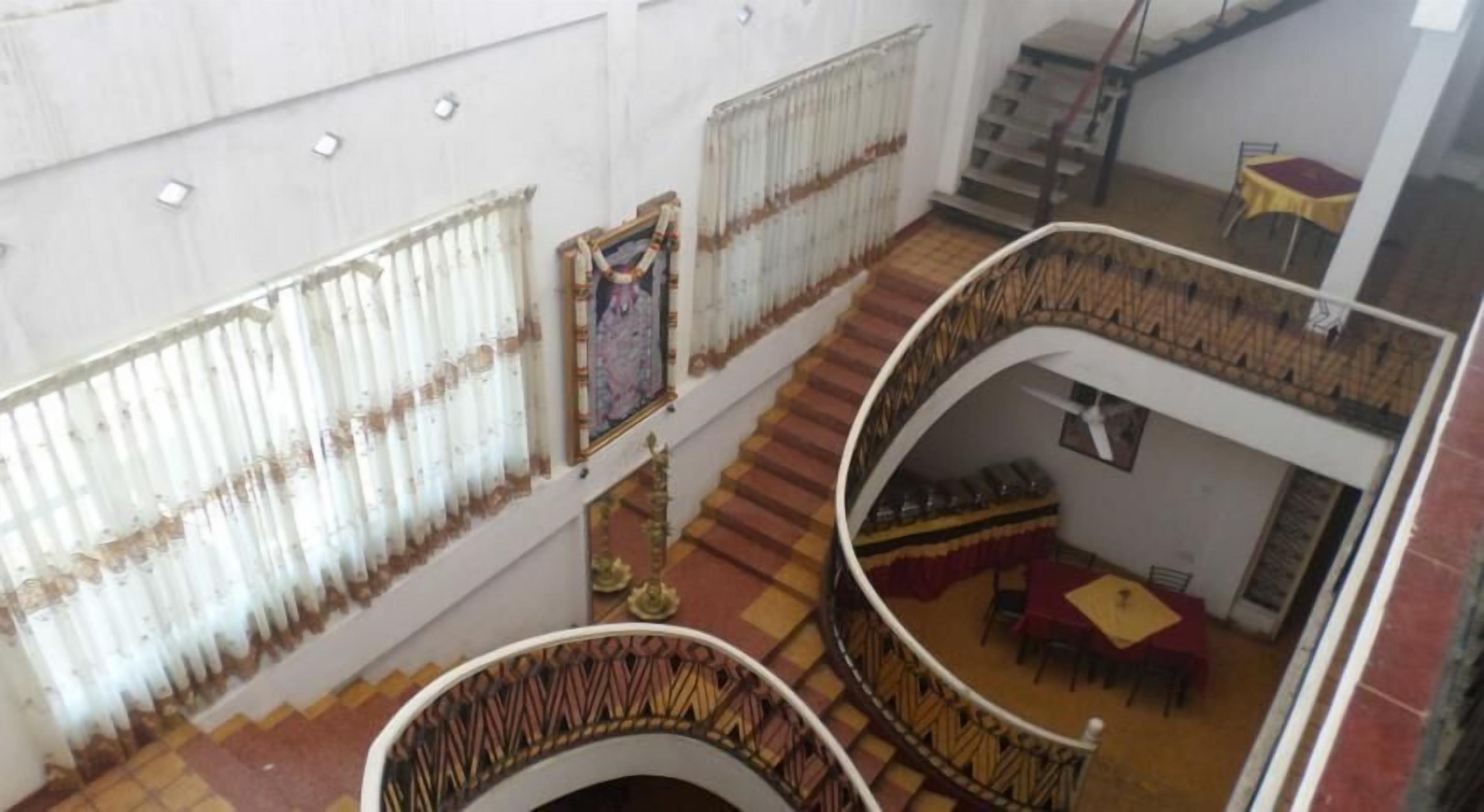 A multi-level interior with a staircase, a dining area with tables and chairs, and a patterned floor.
