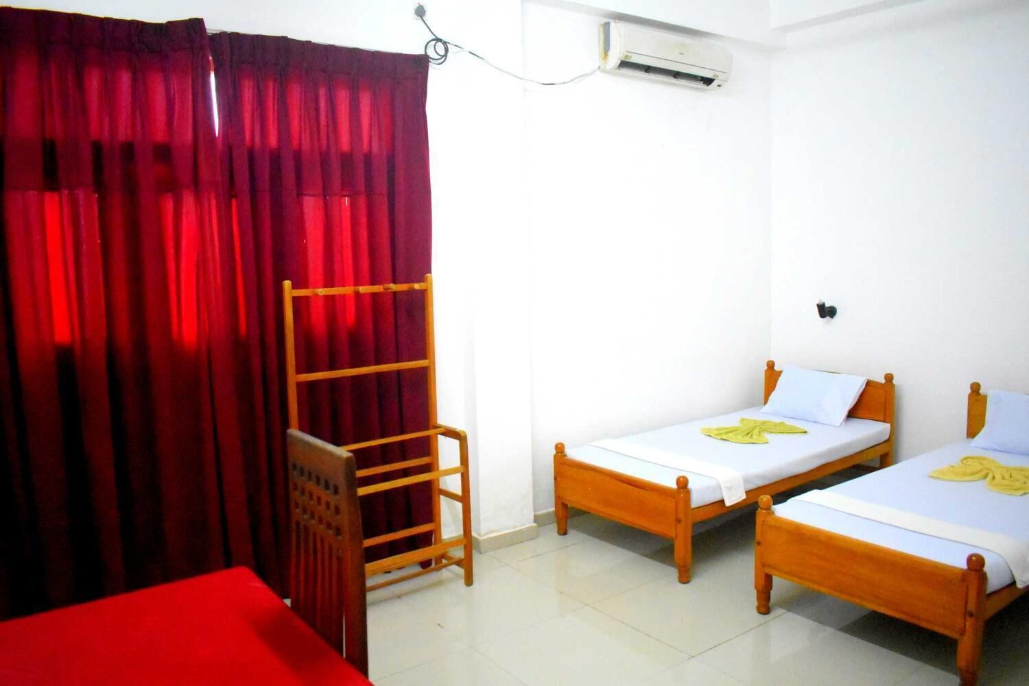 A room with two wooden beds, a red curtain, a wooden ladder, and an air conditioning unit.