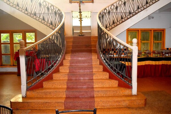 A grand staircase with ornate railings, leading to a room with a buffet setup.