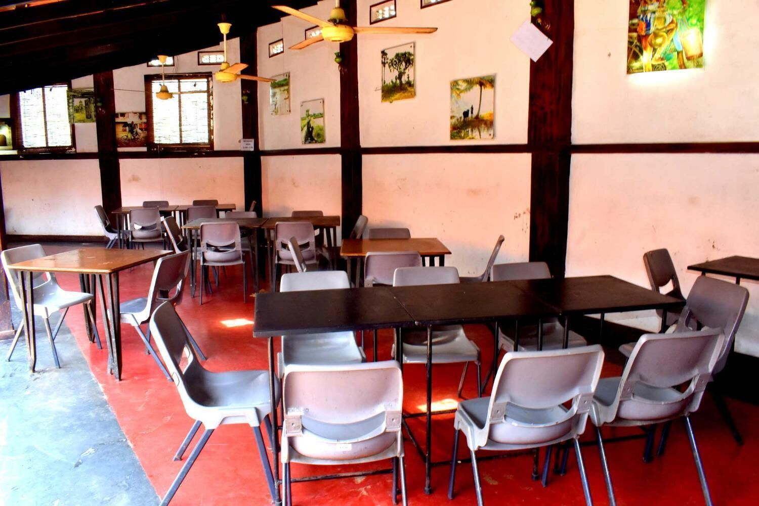 A dining area with tables and chairs, ceiling fans, and wall-mounted artwork.