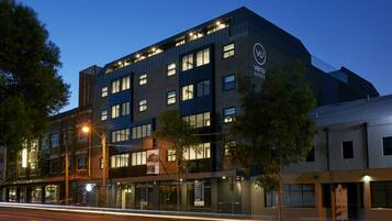 A modern building with multiple floors, large windows, and a prominent logo on the side.