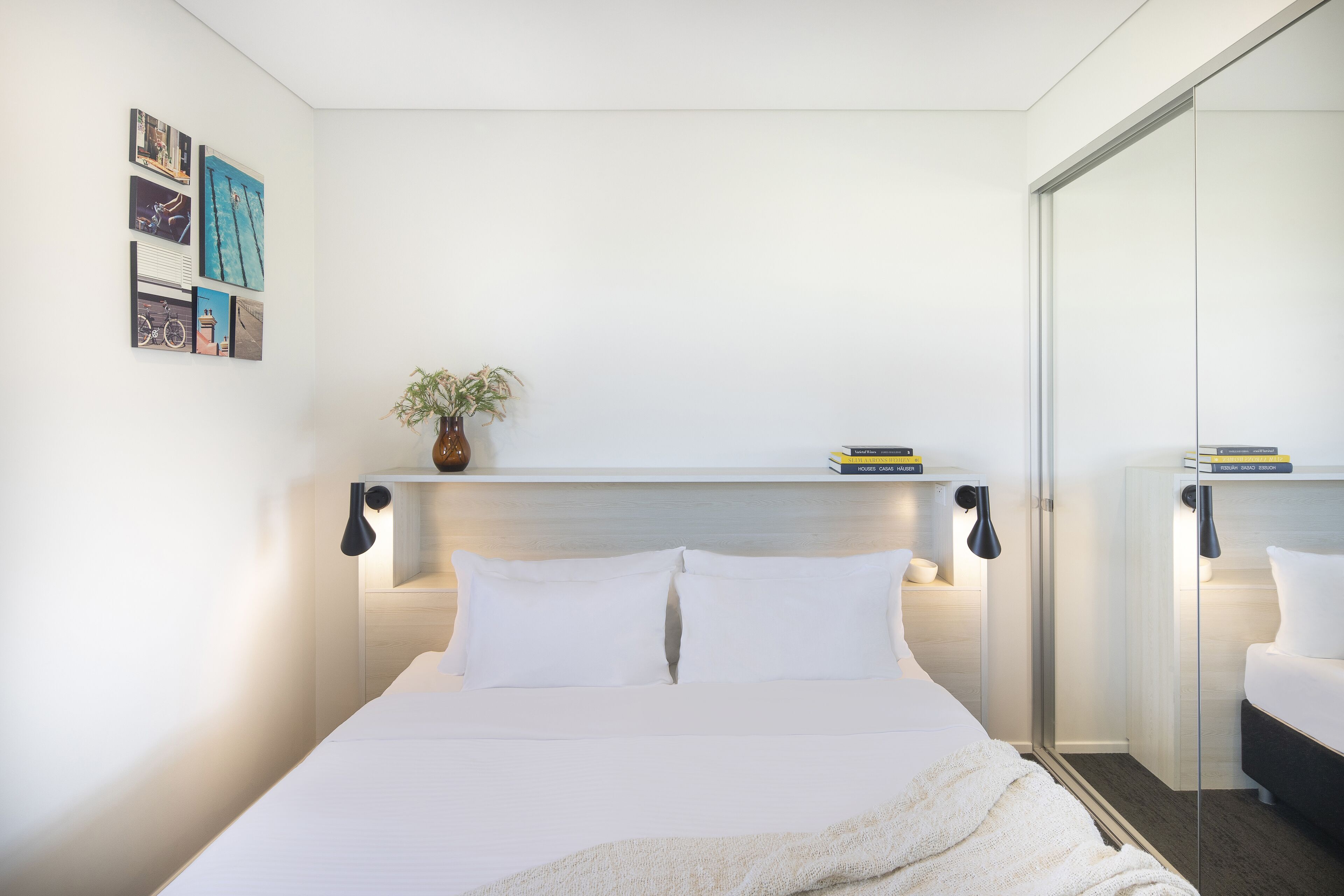 Una camera da letto moderna con un letto grande, comodini, uno specchio e opere d'arte alle pareti.