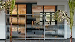 A modern two-story building with a glass balcony, a wooden deck, and a landscaped garden with palm trees. - Veriu Camperdown (Camperdown)
