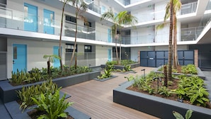 A modern multi-story building with balconies, a rooftop garden, and a wooden deck area. - Veriu Camperdown (Camperdown)