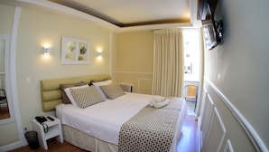 Una habitación de hotel con cama, mesita de noche y televisión montada en la pared.