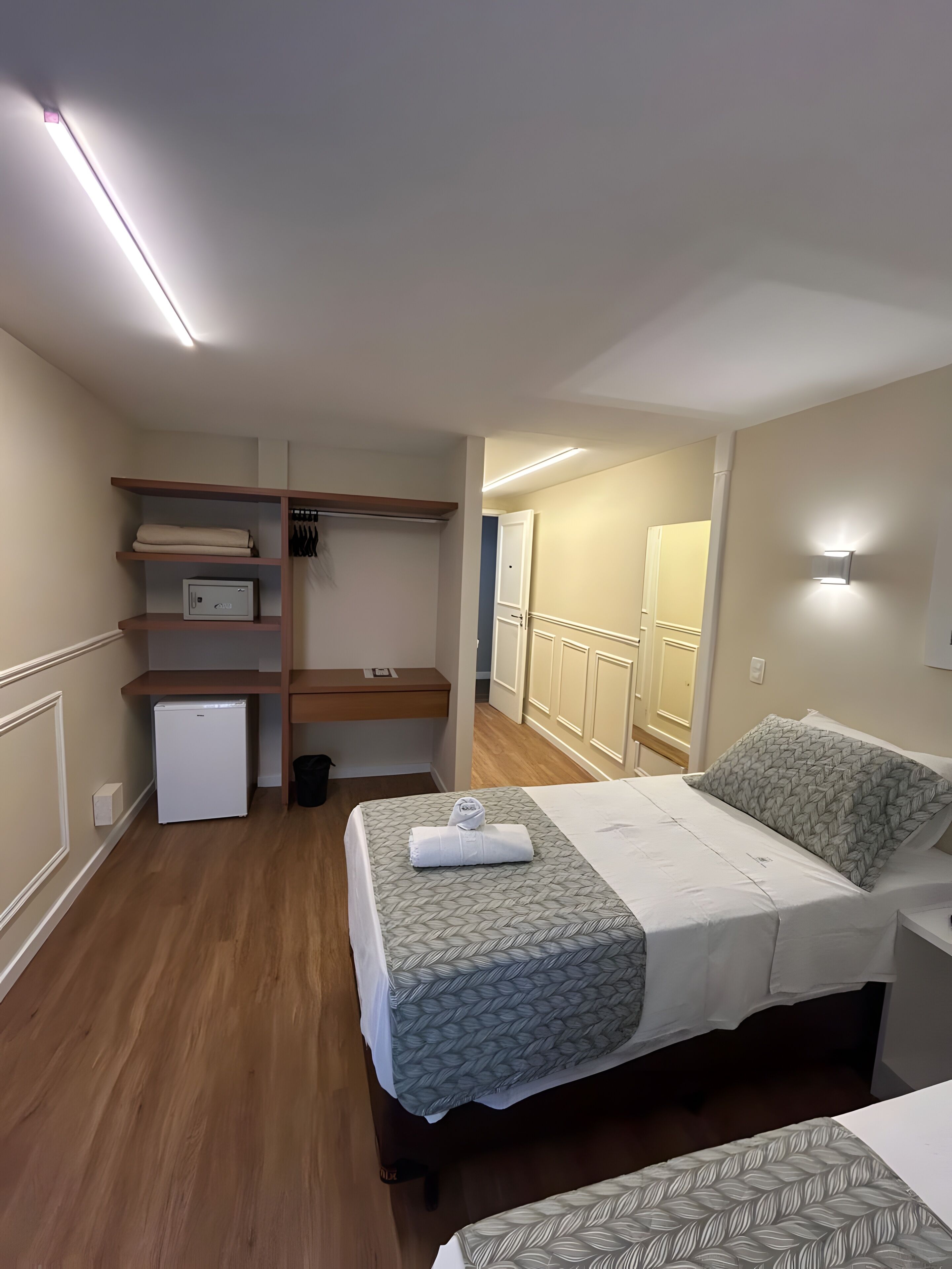 Ein Schlafzimmer mit einem Bett, einem kleinen Kühlschrank, einem Kleiderschrank und einem Nachttisch.