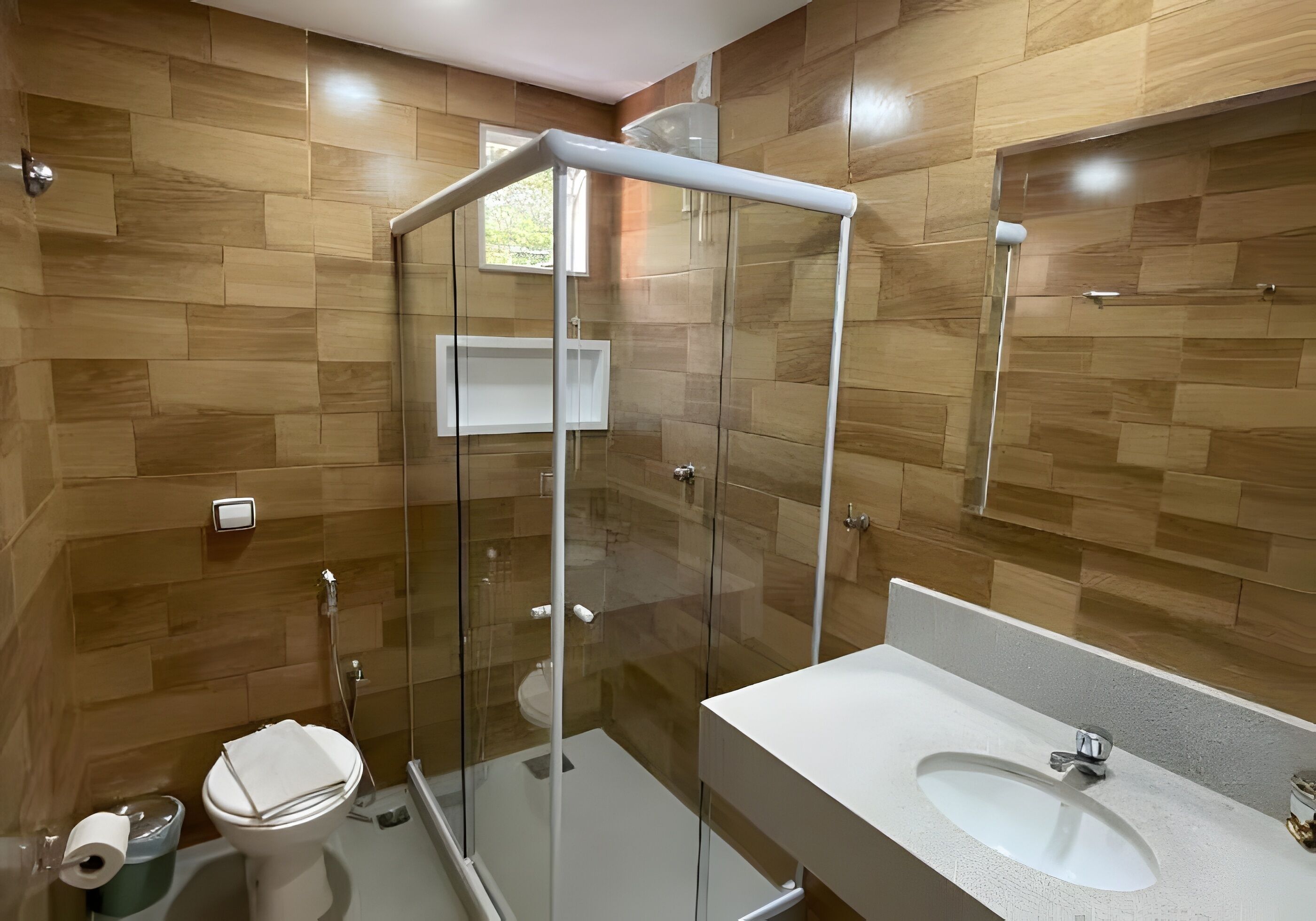 Een moderne badkamer met een douchecabine van glas, toilet en een wastafel met spiegel.