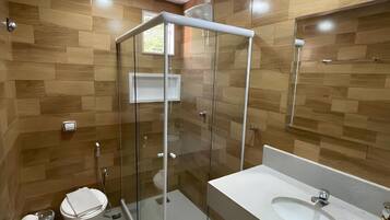 Een moderne badkamer met een douchecabine van glas, toilet en een wastafel met spiegel.